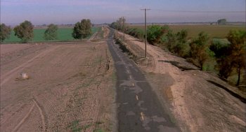 Movie still from “Dirty Mary Crazy Larry” (1974), directed by John Hough – An aerial view of an empty road in the middle of a field; Extreme Wide shot, High angle