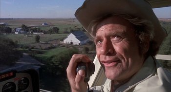 Movie still from “Dirty Mary Crazy Larry” (1974), directed by John Hough – An older man talking on a cell phone while standing in a field; Close Up shot, Low angle