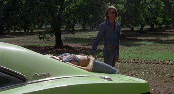 Movie still from “Dirty Mary Crazy Larry” (1974), directed by John Hough – A woman standing in front of a green car; Wide shot, Low angle