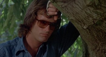 Movie still from “Dirty Mary Crazy Larry” (1974), directed by John Hough – A man with sunglasses leaning on a tree; Close Up shot, Low angle