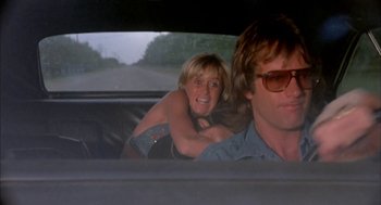Movie still from “Dirty Mary Crazy Larry” (1974), directed by John Hough – A man and a woman riding in the back of a car; Medium shot, Low angle