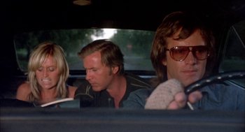 Movie still from “Dirty Mary Crazy Larry” (1974), directed by John Hough – A group of people sitting in the back of a car; Medium shot, Low angle