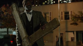 Movie still from “Do You Believe?” (2015), directed by Jon Gunn – A man in a suit and tie holding a piece of wood; Medium shot, Low angle