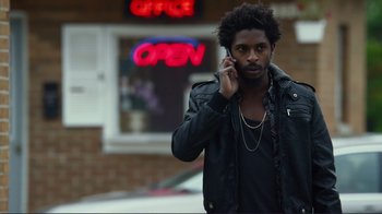 Movie still from “Do You Believe?” (2015), directed by Jon Gunn – A man talking on a cell phone while standing on the street; Medium shot, Low angle