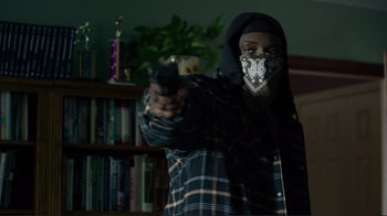 Movie still from “Do You Believe?” (2015), directed by Jon Gunn – A person with a face mask holding a gun; Medium shot, Low angle