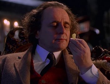 Movie still from “Doctor Who: The Movie” (1996), directed by Geoffrey Sax – A man in a suit and tie holding a piece of food; Close Up shot, Over the shoulder angle