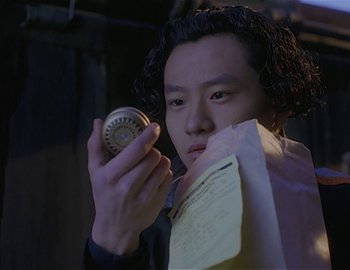 Movie still from “Doctor Who: The Movie” (1996), directed by Geoffrey Sax – A man holding a paper and a watch; Close Up shot, High angle