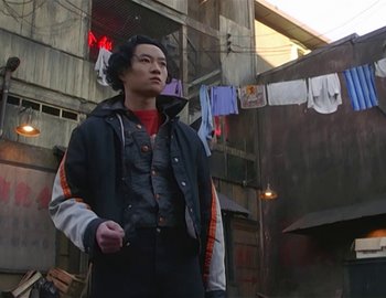 Movie still from “Doctor Who: The Movie” (1996), directed by Geoffrey Sax – A man standing in front of a building with clothes hanging on a clothesline; Medium shot, Low angle