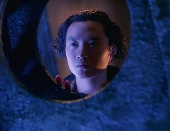 Movie still from “Doctor Who: The Movie” (1996), directed by Geoffrey Sax – A young man looking through a hole in a wall; Close Up shot, Low angle