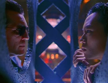 Movie still from “Doctor Who: The Movie” (1996), directed by Geoffrey Sax – A man in a suit and sunglasses looking at another man in a suit and sunglasses; Close Up shot, Low angle