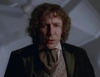 Movie still from “Doctor Who: The Movie” (1996), directed by Geoffrey Sax – A man with curly hair wearing a suit and tie; Close Up shot, Low angle