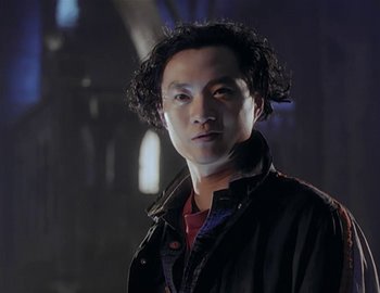 Movie still from “Doctor Who: The Movie” (1996), directed by Geoffrey Sax – A man in a black jacket is standing in a dark room; Close Up shot, Low angle