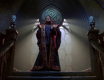 Movie still from “Doctor Who: The Movie” (1996), directed by Geoffrey Sax – A man dressed as a wizard standing in front of a stained glass window; Wide shot, Low angle