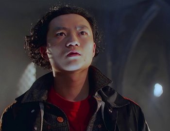 Movie still from “Doctor Who: The Movie” (1996), directed by Geoffrey Sax – A man with curly hair wearing a red shirt and a black jacket; Close Up shot, Low angle