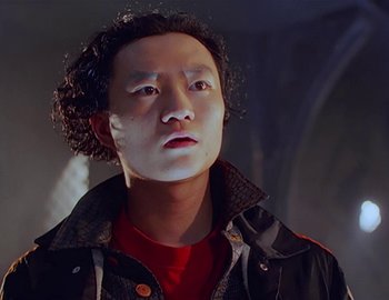 Movie still from “Doctor Who: The Movie” (1996), directed by Geoffrey Sax – A young man with curly black hair wearing a red shirt and a black jacket; Close Up shot, Low angle