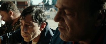 Movie still from “Dogman” (2018), directed by Matteo Garrone – Two men sitting next to each other on a dirt road; Close Up shot, Over the shoulder angle
