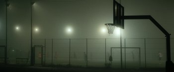 Movie still from “Dogman” (2018), directed by Matteo Garrone – A group of people playing basketball in the fog; Extreme Wide shot, High angle