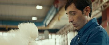 Movie still from “Dogman” (2018), directed by Matteo Garrone – A man looking down at a cotton candy while standing next to him; Close Up shot, Over the shoulder angle