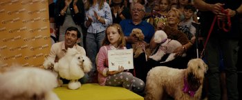 Movie still from “Dogman” (2018), directed by Matteo Garrone – A group of people watching a girl hold a certificate; Medium shot, Over the shoulder angle