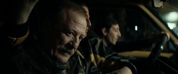 Movie still from “Dogman” (2018), directed by Matteo Garrone – A group of men sitting next to each other in a dark room; Close Up shot, Over the shoulder angle
