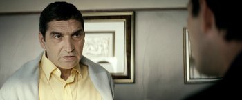 Movie still from “Dogman” (2018), directed by Matteo Garrone – An older man wearing a yellow shirt and a white jacket; Close Up shot, Over the shoulder angle