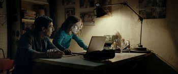 Movie still from “Dogman” (2018), directed by Matteo Garrone – A little girl using a computer on a desk; Medium shot, Over the shoulder angle