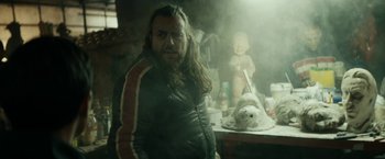 Movie still from “Dogman” (2018), directed by Matteo Garrone – A man with a long beard standing next to a teddy bear; Close Up shot, Over the shoulder angle