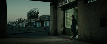 Movie still from “Dogman” (2018), directed by Matteo Garrone – A man standing in front of a storefront window; Wide shot, Over the shoulder angle