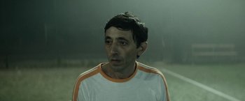 Movie still from “Dogman” (2018), directed by Matteo Garrone – A person wearing a white and orange shirt; Close Up shot, Low angle