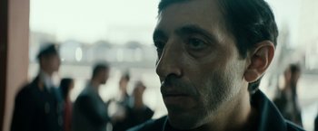 Movie still from “Dogman” (2018), directed by Matteo Garrone – A man's face with people in the background; Close Up shot, Low angle