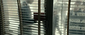 Movie still from “Dogman” (2018), directed by Matteo Garrone – A red box sitting on top of an open window; Medium shot, Over the shoulder angle
