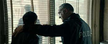 Movie still from “Dogman” (2018), directed by Matteo Garrone – A man holding a gun pointed at another man; Medium shot, Over the shoulder angle