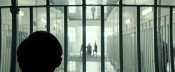 Movie still from “Dogman” (2018), directed by Matteo Garrone – A group of people standing in a room with bars; Extreme Close Up shot, Over the shoulder angle