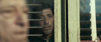 Movie still from “Dogman” (2018), directed by Matteo Garrone – A person looking out of a window; Close Up shot, Low angle
