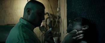 Movie still from “Dogman” (2018), directed by Matteo Garrone – A man holding a cell phone in his hand while looking at another man's face; Close Up shot, Over the shoulder angle