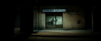 Movie still from “Dogman” (2018), directed by Matteo Garrone – A man standing in front of a storefront window at night; Extreme Wide shot, High angle