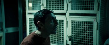 Movie still from “Dogman” (2018), directed by Matteo Garrone – A man looking up into the air in front of some cages; Close Up shot, Low angle