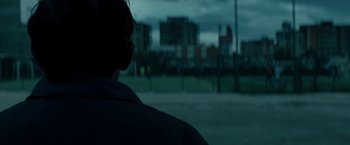 Movie still from “Dogman” (2018), directed by Matteo Garrone – A man standing in front of a fence looking out at a city skyline; Extreme Close Up shot, Over the shoulder angle
