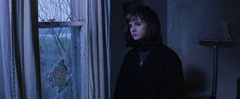 Movie still from “Dolores Claiborne” (1995), directed by Taylor Hackford – A young woman standing in front of a window in a dark room; Close Up shot, Over the shoulder angle