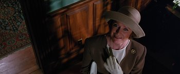 Movie still from “Dolores Claiborne” (1995), directed by Taylor Hackford – An older woman wearing a hat and gloves in front of a wooden cabinet; Close Up shot, Low angle