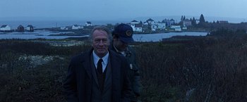 Movie still from “Dolores Claiborne” (1995), directed by Taylor Hackford – A man in a suit standing next to another man in a hat; Medium shot, Over the shoulder angle