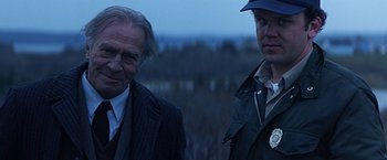 Movie still from “Dolores Claiborne” (1995), directed by Taylor Hackford – Two men standing next to each other on a field; Close Up shot, Over the shoulder angle