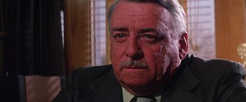 Movie still from “Dolores Claiborne” (1995), directed by Taylor Hackford – An older man wearing a suit and tie looking sad; Close Up shot, Low angle