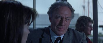 Movie still from “Dolores Claiborne” (1995), directed by Taylor Hackford – An older man wearing a suit and tie in front of a window; Close Up shot, Over the shoulder angle