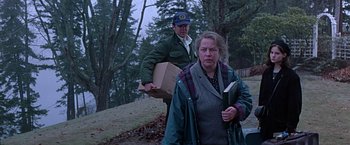Movie still from “Dolores Claiborne” (1995), directed by Taylor Hackford – A man and a woman walking in a wooded area carrying boxes; Medium shot, Low angle