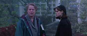 Movie still from “Dolores Claiborne” (1995), directed by Taylor Hackford – Two women standing next to each other outside; Medium shot, Low angle