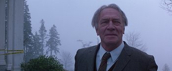 An older man wearing a suit and tie in the fog
