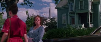 Movie still from “Dolores Claiborne” (1995), directed by Taylor Hackford – A woman standing in front of a house with a church in the background; Medium shot, Low angle