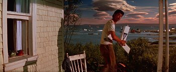 Movie still from “Dolores Claiborne” (1995), directed by Taylor Hackford – A man standing in front of the ocean with boats in the background; Wide shot, Low angle
