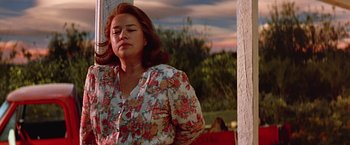 Movie still from “Dolores Claiborne” (1995), directed by Taylor Hackford – A woman in a flowery shirt is standing outside; Medium shot, Low angle